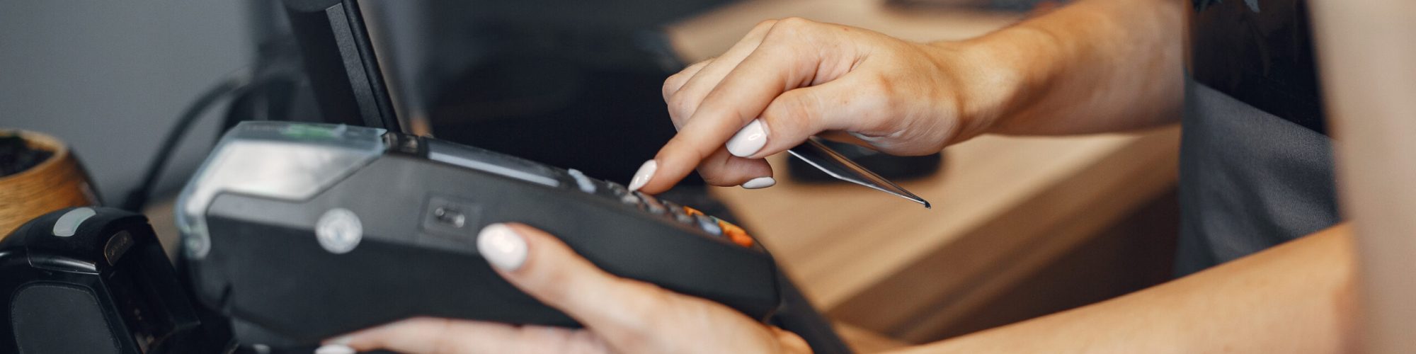 Womanl pays for the purchase. Credit card in hand. Lady uses the terminal.